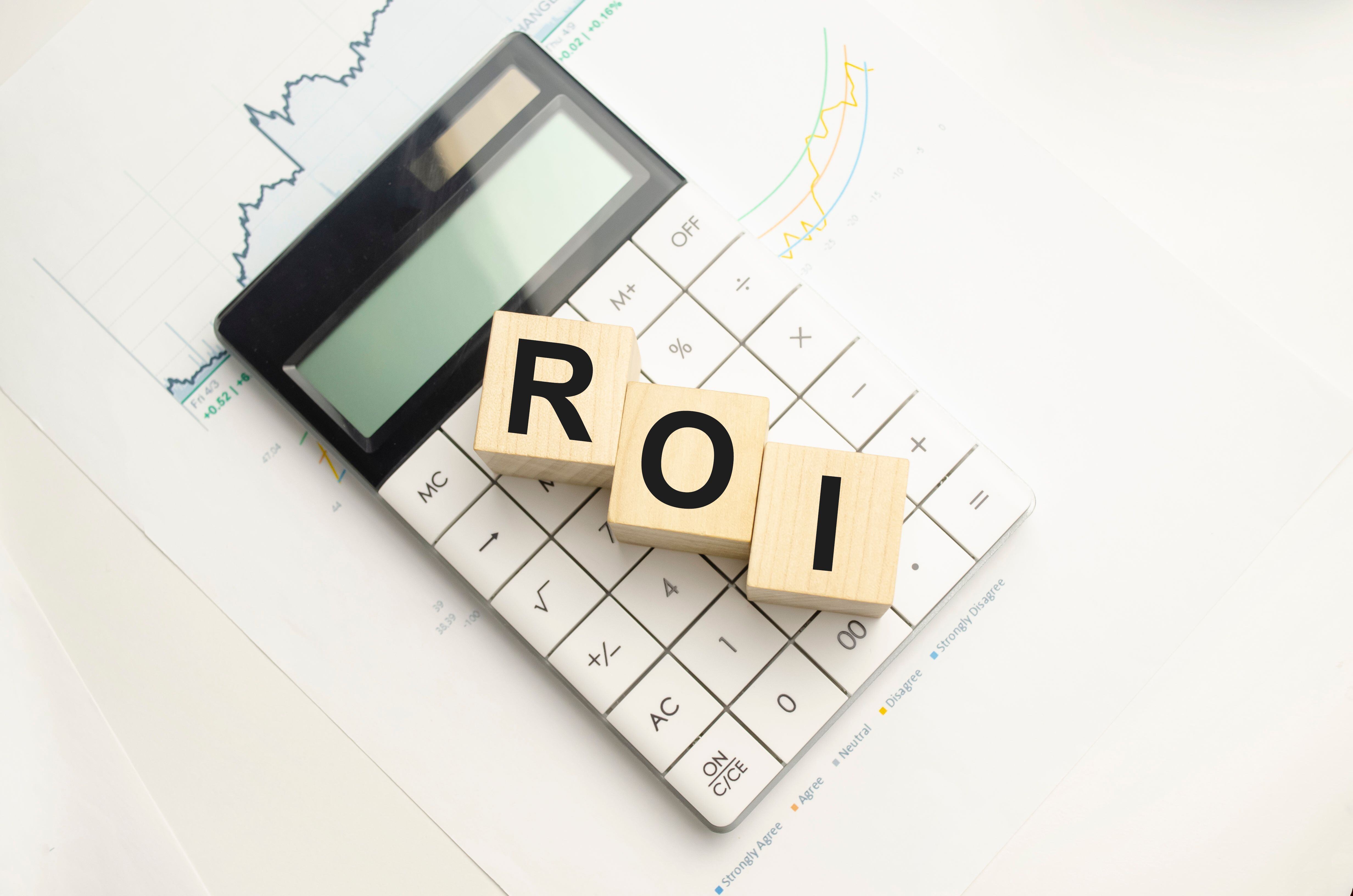 roi-return-investment-written-wooden-cubes-calculator-pen-light-background-investment-concept-high-quality-photo